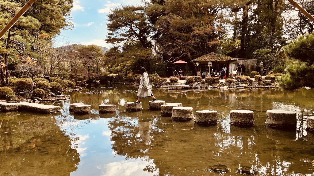 京都・平安神宮神苑の臥龍橋を渡りながら池に映る空と庭園を楽しむ風景