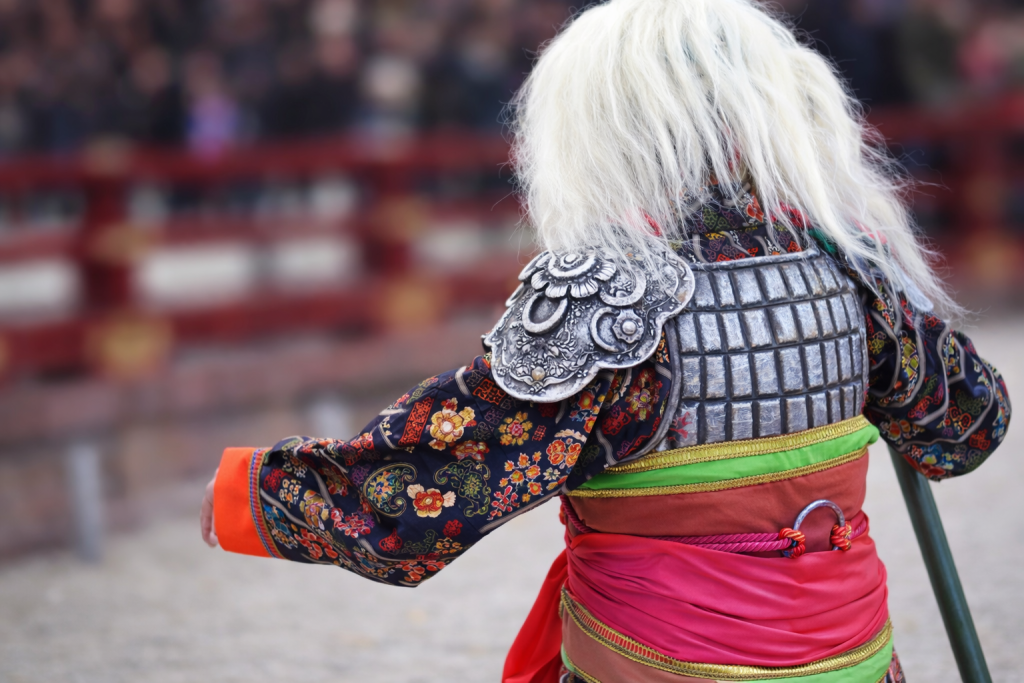 節分の行事で登場する鬼の後ろ姿。白い髪と色鮮やかな衣装をまとい、本殿前で豆を受けながら進んでいく様子