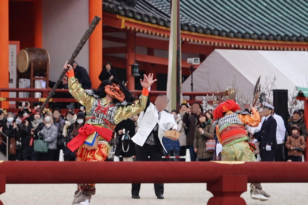 平安神宮の節分行事で、豆を受けながら舞う鬼たち。武器を手に力強く動き回り、厄を祓う様子を表現している場面