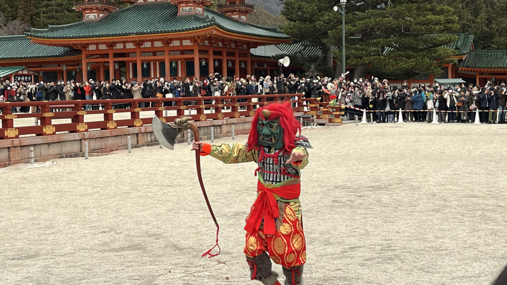 平安神宮の境内を逃げる節分の鬼。豆を受けながら武器を手に走り、参拝者に囲まれて追い払われていく様子