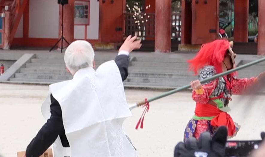 平安神宮の節分行事で、豆を投げられながら逃げる鬼。参拝者の前で追い払われ、大手門へ向かっていく場面