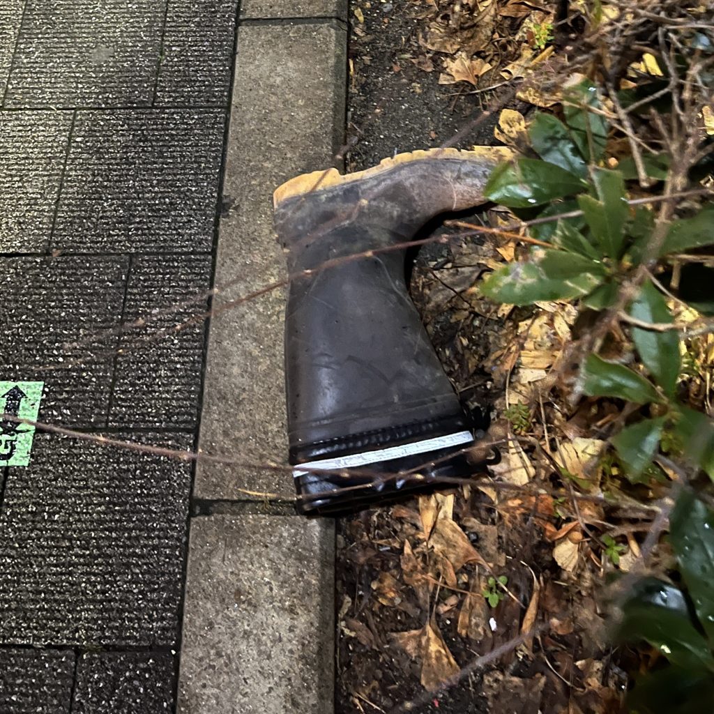 歩道の端の植え込みのそばによせられていた落とし物の片方の長靴