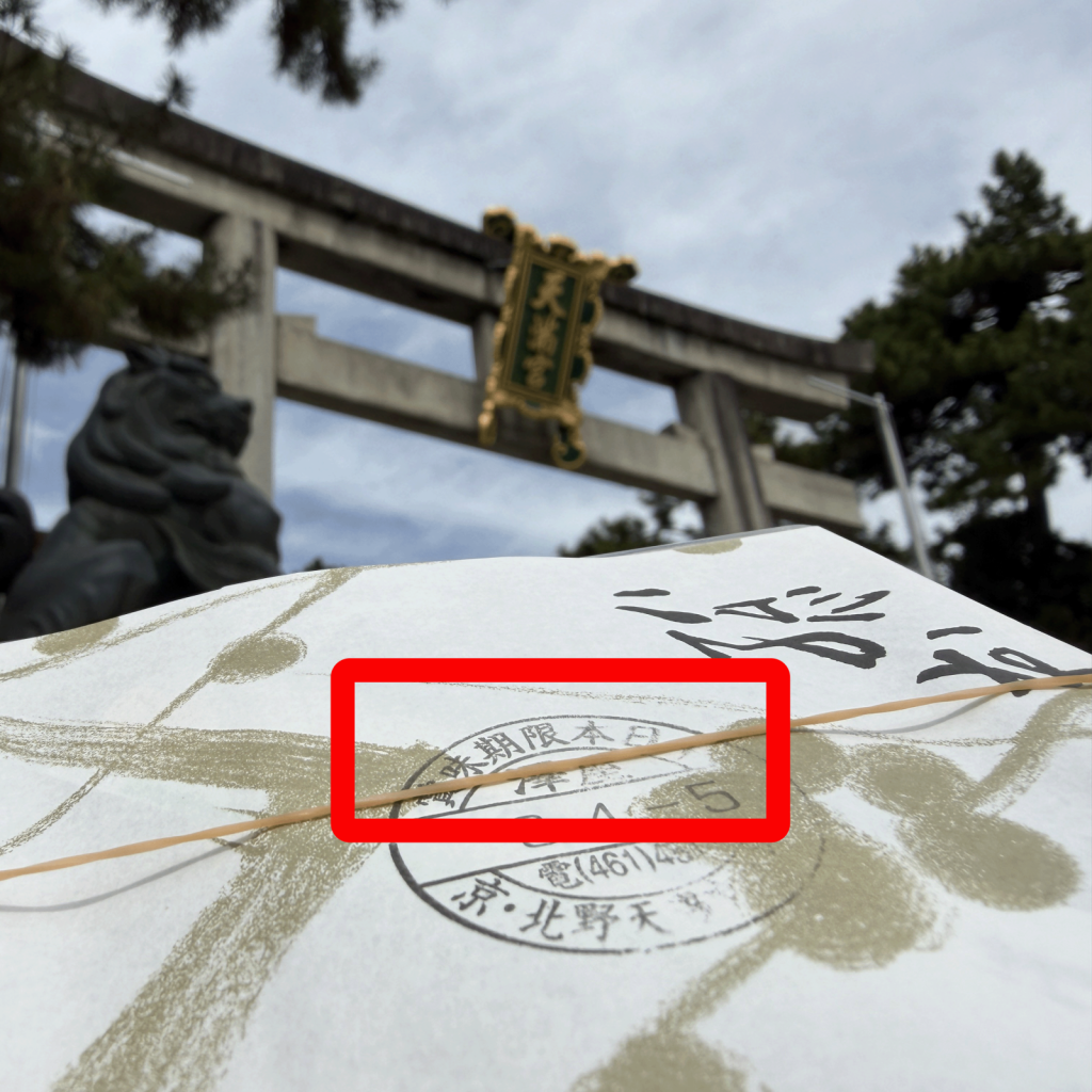 北野天満宮の鳥居を背景に澤屋の包み紙に押された賞味期限本日のスタンプ