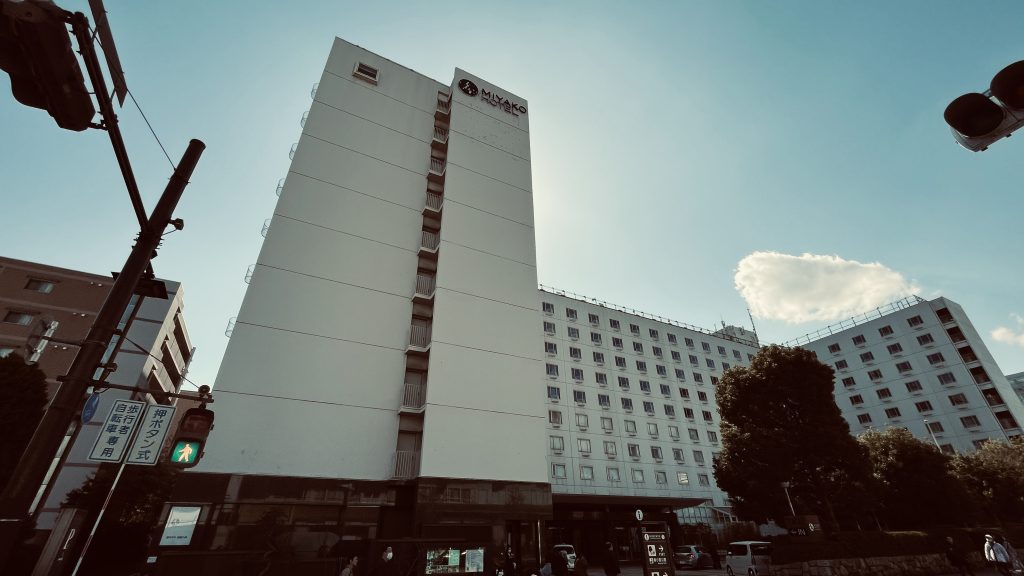 都ホテル京都八条の外観（交差点から見上げる白い建物と青空）