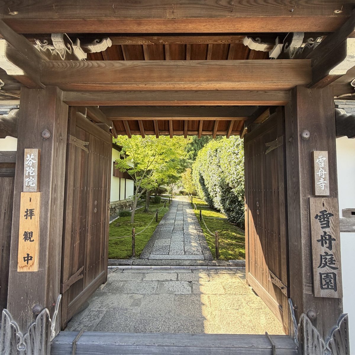 「雪舟寺」「雪舟庭園」の札がかかった門から見える石畳の参道